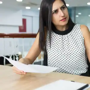 mployee reviewing confusing paperwork while on a stressful work call