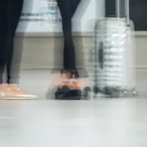 Blurred travelers walking through an airport terminal with a suitcase, representing airport negligence