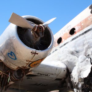 Damaged commercial airplane with visible engine destruction and emergency crew on site
