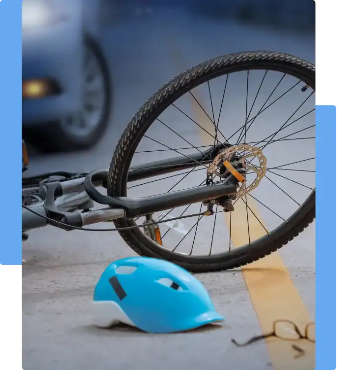 Cyclist injury Close-up of a fallen bicycle on the road with a blue helmet and eyeglasses on the ground, suggesting a recent cyclist accident involving a car in the background.