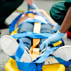 Emergency responders secure an injured person to a stretcher after a serious accident