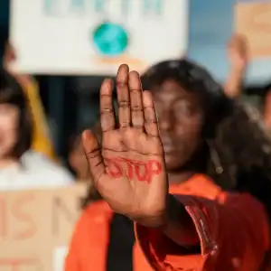 Protester holding up hand with 'STOP' written on it, symbolizing freedom of speech and protest