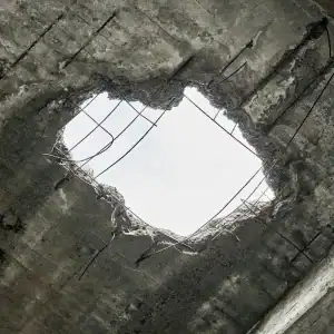 Large hole in a concrete ceiling exposing sky, representing structural hazard