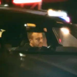 Driver inside a vehicle at night with police lights reflecting on the window