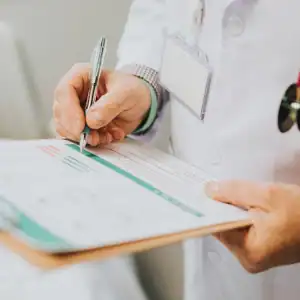 Doctor filling out medical forms related to accident injury documentation
