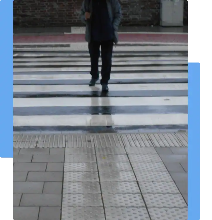 Pedestrian crossing a wet striped crosswalk, representing the risks and legal implications of pedestrian injury accidents