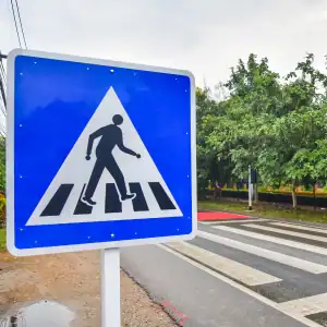 Pedestrian crossing sign near marked crosswalk in urban area
