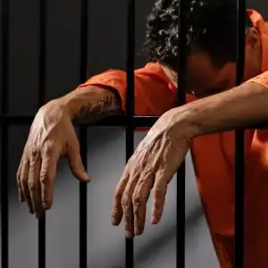 Incarcerated person leaning on prison bars, reflecting the struggle for prisoners’ rights