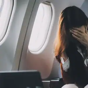 Passenger covering her face during in-flight turbulence inside a commercial airplane