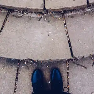 Person standing on cracked and uneven pavement with visible gaps and roots