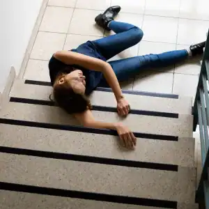 Slip and fall lawyer Woman lying on stairs after a fall, showing the risk of unsafe staircases