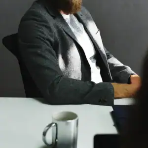 Professional man seated in a formal meeting, suggesting workplace negotiation or legal consultation