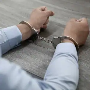 Person in handcuffs at a table, representing wrongful imprisonment.