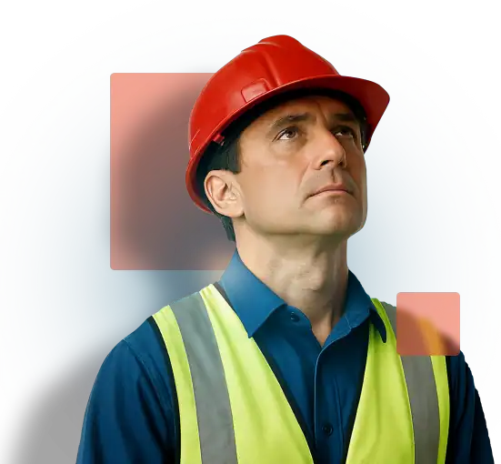 Construction worker wearing safety gear and looking up, assessing potential hazards on site